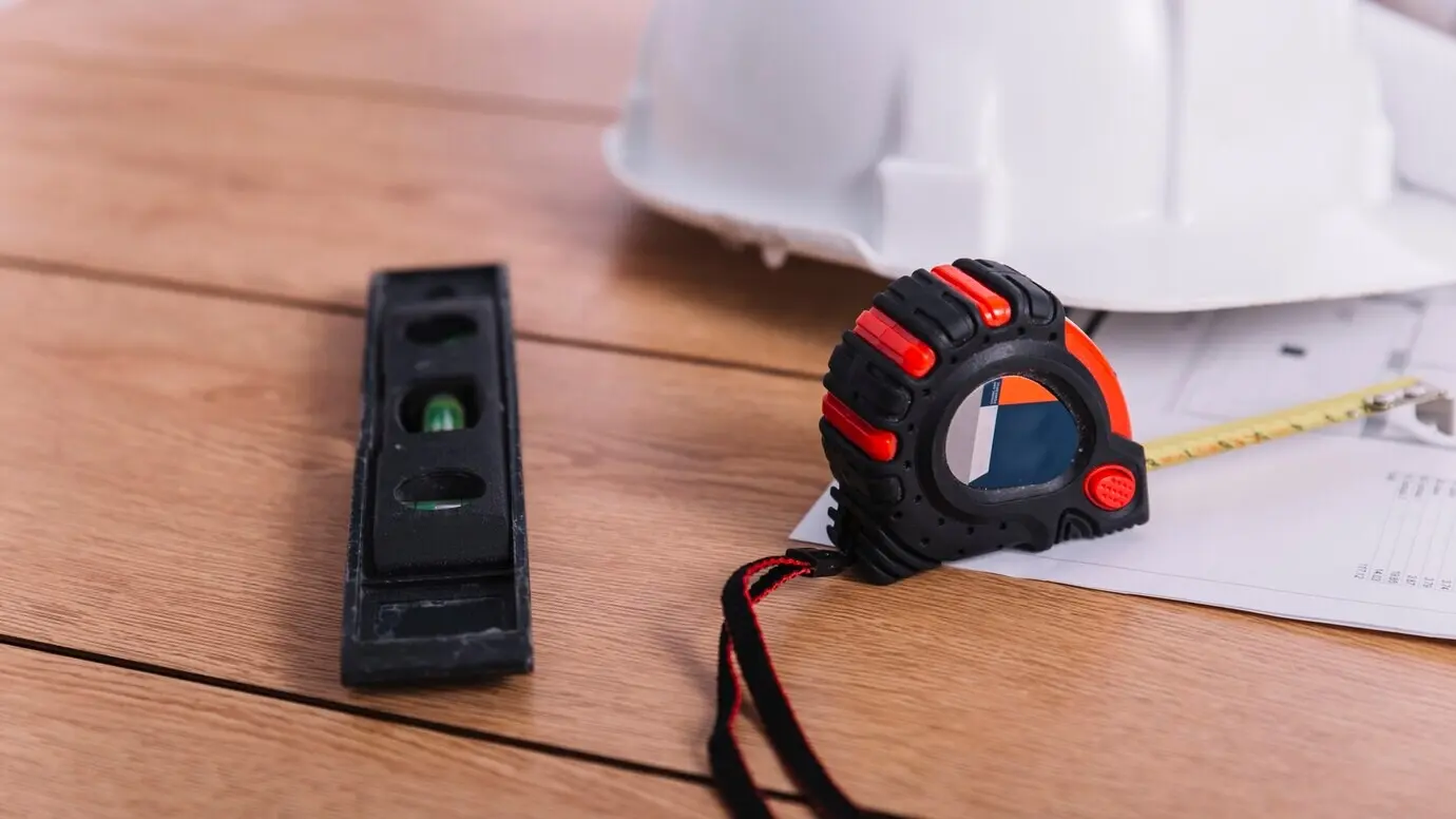 Primer plano de una cinta métrica y un nivel cerca de un casco.